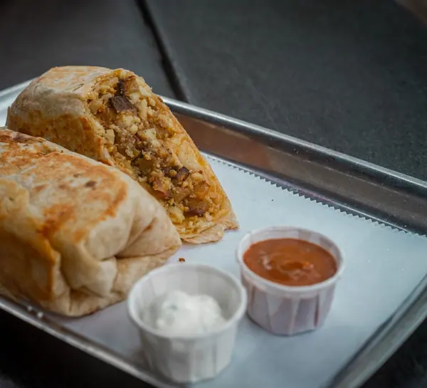 A burrito cut in half with two dips